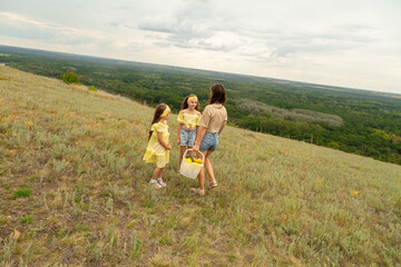 Obraz premium Family on a meadow, mother and daughter holding hands while carries picnic basket