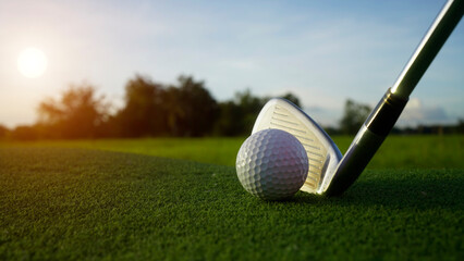 Golf clubs and balls on a green lawn in a beautiful golf course with morning sunshine.