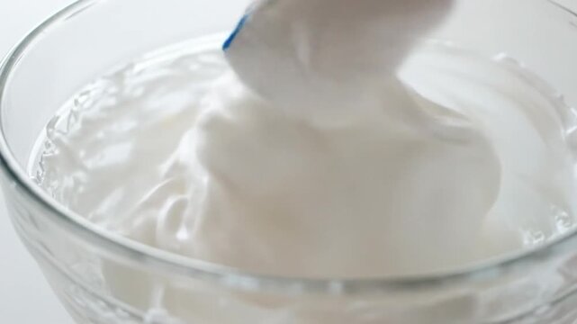 Close up of creamy batter being mixed in a glass bowl with a spatula.