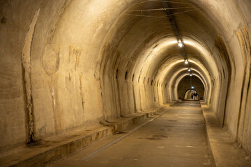 Zagreb, Croatia - August 23, 2024: Illuminated underground tunnel in Zagreb with arched concrete walls and a long perspective view leading toward distant figures.