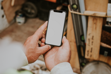 Man holding png smartphone mockup near a construction site