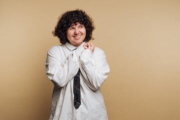 portrait of young excited woman clasping hands with a joyful expression while wearing a white shirt...