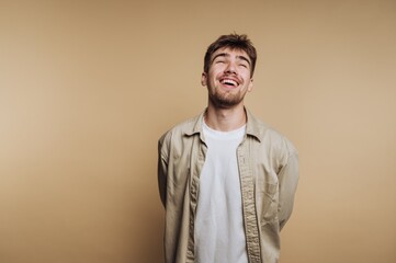 portrait of young smiling man exudes happiness in a light studio setting, capturing a moment of joy on beige background
