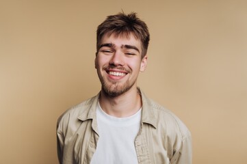 portrait of young man stands smiling brightly against a tan background, embodying joy and warmth on beige background