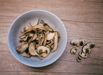 Dried mushrooms in a brown bowl on a wooden table. Natural dehydrated porcini slices prepared for cooking and seasoning.