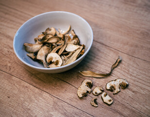 Dried mushrooms in a brown bowl on a wooden table. Natural dehydrated porcini slices prepared for cooking and seasoning.