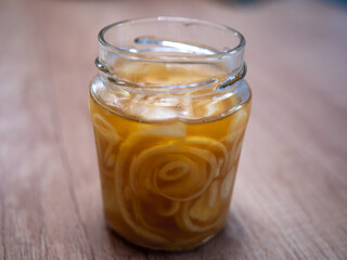Homemade onion syrup with lemon and honey in a glass jar on a wooden table. Natural home remedy for sore throat and cough relief.