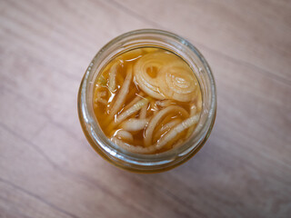 Homemade onion syrup with lemon and honey in a glass jar on a wooden table. Natural home remedy for sore throat and cough relief.