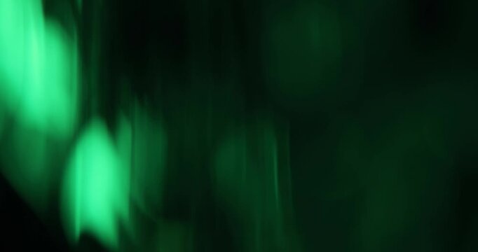 Abstract green blurred light leaks on dark background with copy space for design. Studio anamorphic lens flare bokeh effect for title or logo display.