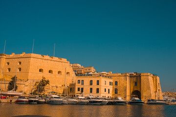 Fototapeta premium Birgu Waterfront, Malta – Boats, Historic Cathedrals and Old Town View