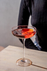 red cocktail in elegant coupe glass on light table