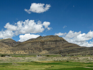 Vast mountain range under a clear blue sky with scattered clouds