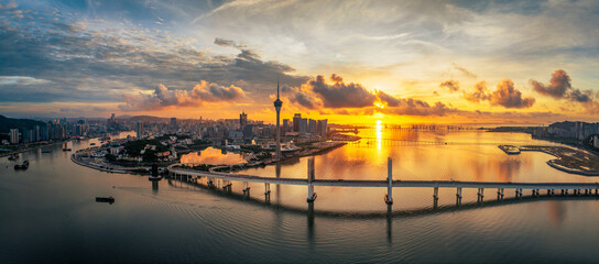 Aerial view of the city skyline and a large sea-crossing bridge with the sun rising brilliantly...
