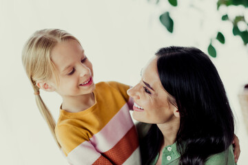 Portrait of a loving mother bonding with her daughter at home, sharing smiles in a comfortable living room atmosphere