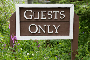 Guests Only as text on a wooden sign in natural green