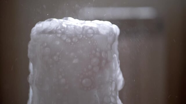 A dramatic effervescent reaction creates a vibrant overflow of white foam and bubbles from a clear glass, capturing dynamic scientific activity. Ideal for abstract and experimental themes. Soda.