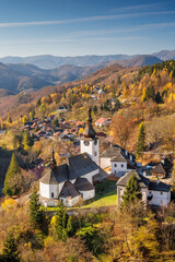The Spania Dolina village in Slovakia, Europe. Picturesque village nestled among rolling hills and autumn foliage, with a prominent church steeple, creating a serene landscape.