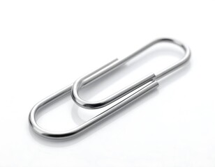 A close-up studio shot displays a single, metallic office supply. The bent, wire shape is highly reflective against a white, glossy surface