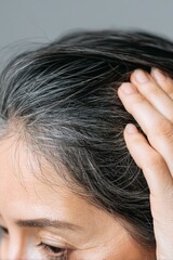 Obraz premium Woman showing gray hair and roots while touching her head with her hand