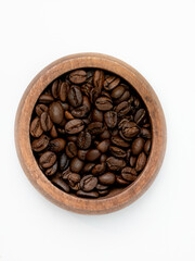Top view of roasted coffee beans in a round wooden bowl isolated on white