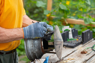 A man wearing gray work gloves holds a chimney cap in his hands.