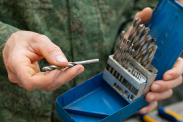 The man holds a set of drill bits in his hands.