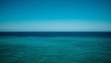 Obraz premium Horizon of the deep blue sea, tranquil ocean vista with a clear sky above, seamless blend of azure and teal waters