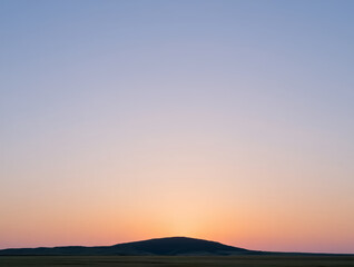 Obraz premium Serene horizon sun setting over rolling hills landscape