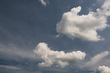 Fototapeta premium A Summer Sky With Several White Cumulus Clouds Floating In A Deep Blue Sky With A Hint Of Cirrus Clouds. Natural Weather Background.