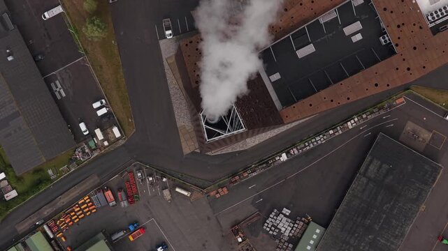 Smoke rising over energy facility, drone aerial of industrial site.