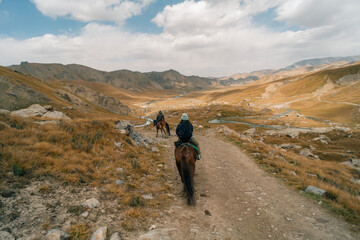 Fototapeta premium Tourists on horseback in Kurumduk valley Naryn province, Kyrgyzstan
