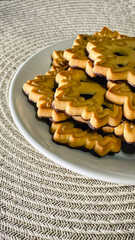 A cozy coffee break with black coffee and golden, patterned butter cookies on a textured surface