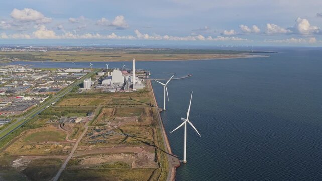 Drone view: wind farm by the Danish coast, turbines aligned at sea.