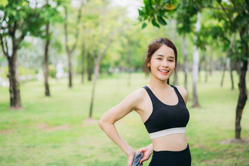 Fototapeta premium Young woman practicing yoga and stretching outdoors in a green park, wearing black sportswear. Healthy lifestyle, fitness training, and relaxation concept in a peaceful natural environment.