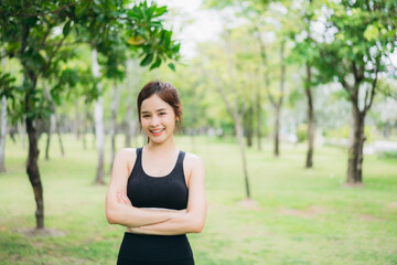 Young woman practicing yoga and stretching outdoors in a green park, wearing black sportswear. Healthy lifestyle, fitness training, and relaxation concept in a peaceful natural environment.