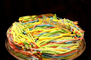 Colorful worm gummy bears sold in a candy store, close-up. Long worm-shaped gummy bears for...