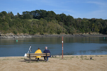 Un couple ssis sur un banc face à la rivière du Jaudy en Bretagne