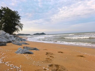The beauty of nature comes alive at the beach, where the waves gently kiss the sandy shore and rocks stand resilient against the tide. This dynamic landscape showcases stunning coastal formations.