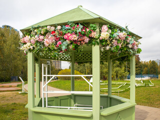 Green gazebo with pastel floral garland in park spring decor