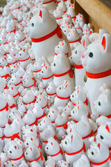 Tokyo, Japan - Sep 30 2024, A close-up view of many multi-sized white beckoning cat figure of Maneki neko with red ears and noses displayed at Gotokuji Temple, without people, at daytime, Tokyo, Japan