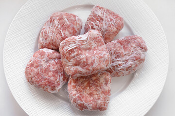 Raw minced pork in plastic wrap or cling film on a plate.
