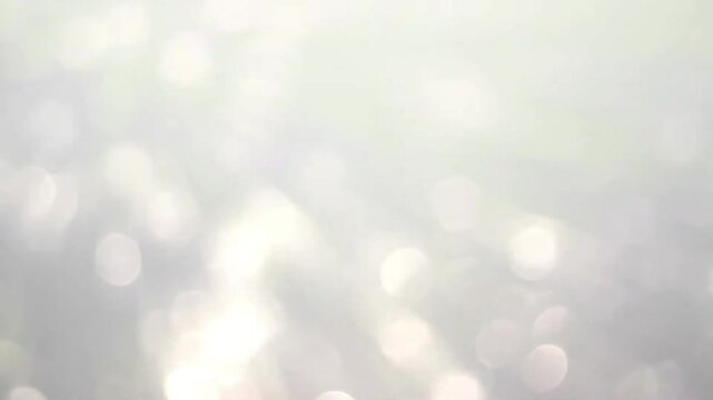 Glowing white bokeh flares motion background with soft sparkling blur effect