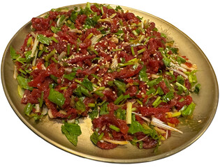 Isolated Korean yukhoe dish with sesame and green herbs on gold plate