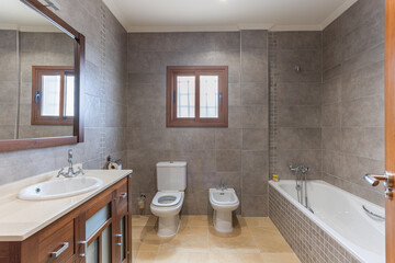 Modern bathroom with bathtub, toilet, bidet, and wooden vanity