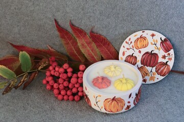 Handmade autumn decorative candle in a plaster jar with painted pumpkins — cozy autumn decor, home fragrance, and festive atmosphere