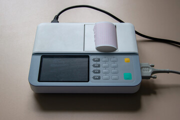 There is an electrocardiograph on the table. On a light brown background.