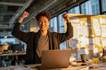 Young man celebrating a successful moment in a modern office environment during the daytime