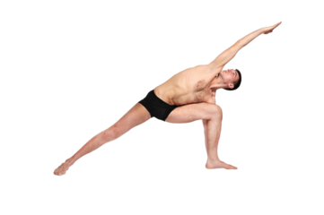 A man practices yoga by raising both arms up in a pose.