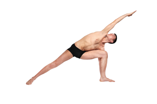 A man practices yoga by raising both arms up in a pose.