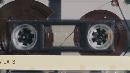 Close up of vintage audio cassette tape spools spinning rapidly showing magnetic tape unwinding and rewinding in a retro analog technology concept